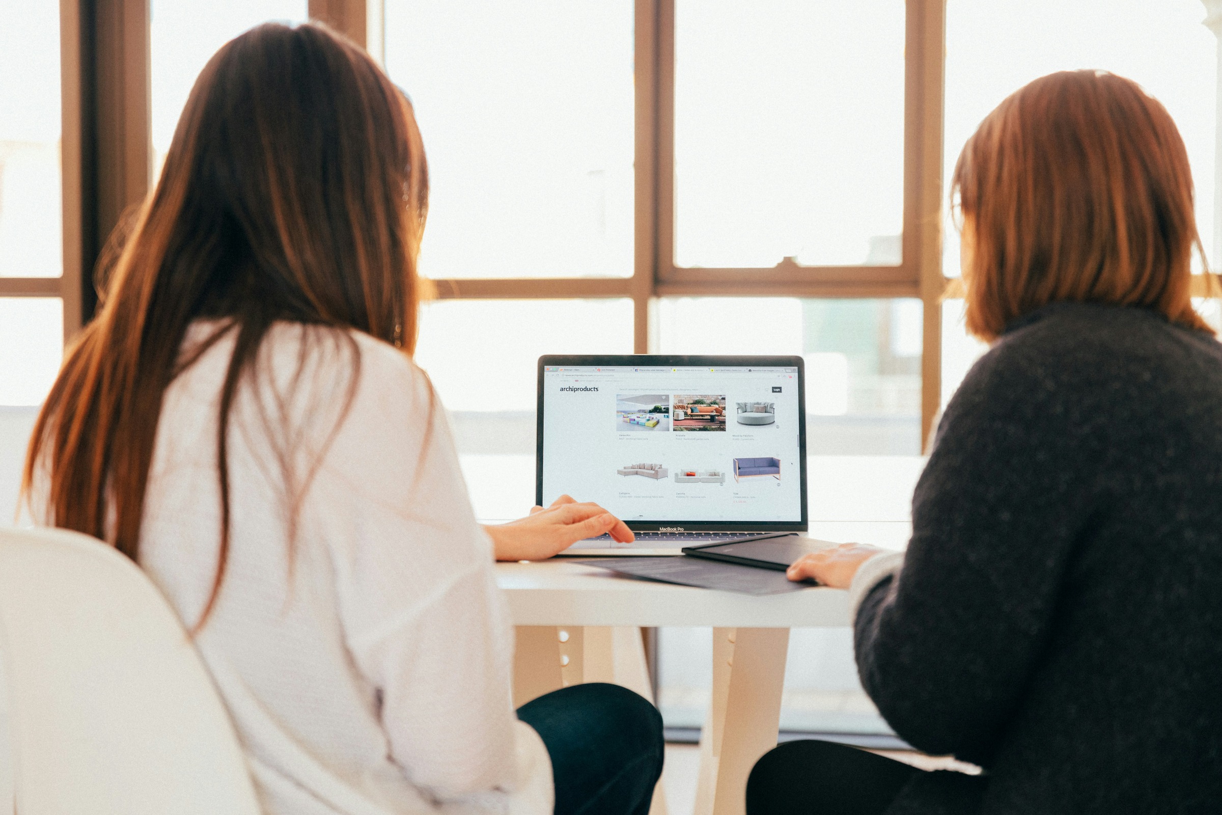 Two women sat looking at a computer screen.