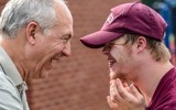 An older man and young man with Downs Syndrome smiling at each other.