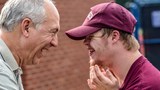 An older man and young man with Downs Syndrome smiling at each other.