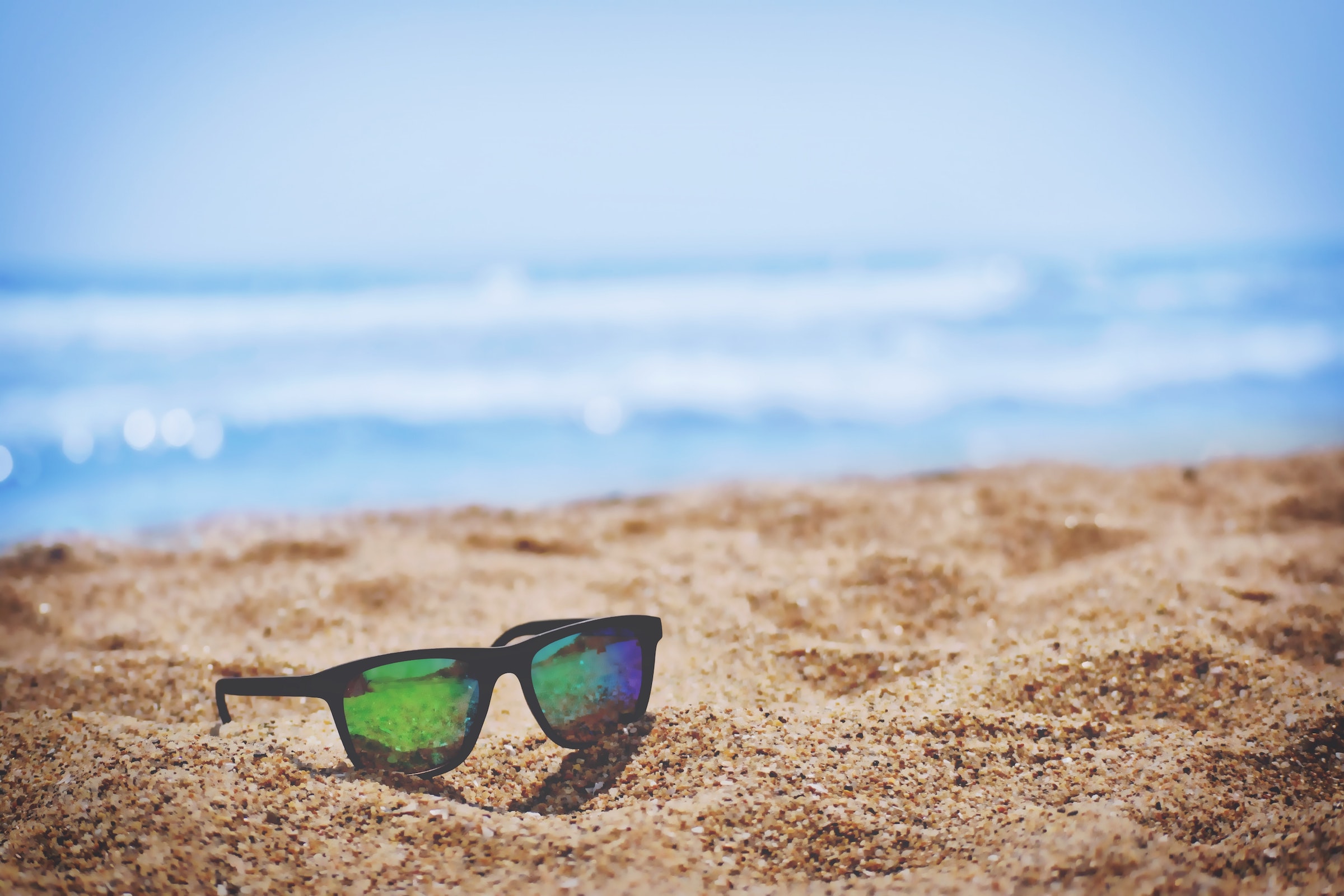 A pair of sunglasses on a sandy beach.