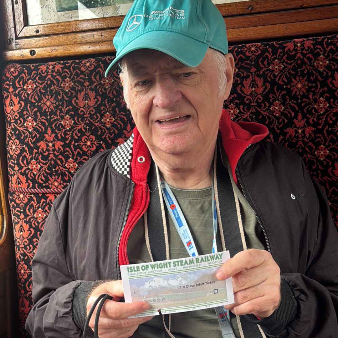 A picture showing AC sitting in a vintage locomotive carriage holding his train ticket