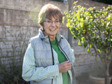 An older woman standing in a garden smiling