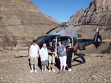 A group of people stood in front a a helicopter. 