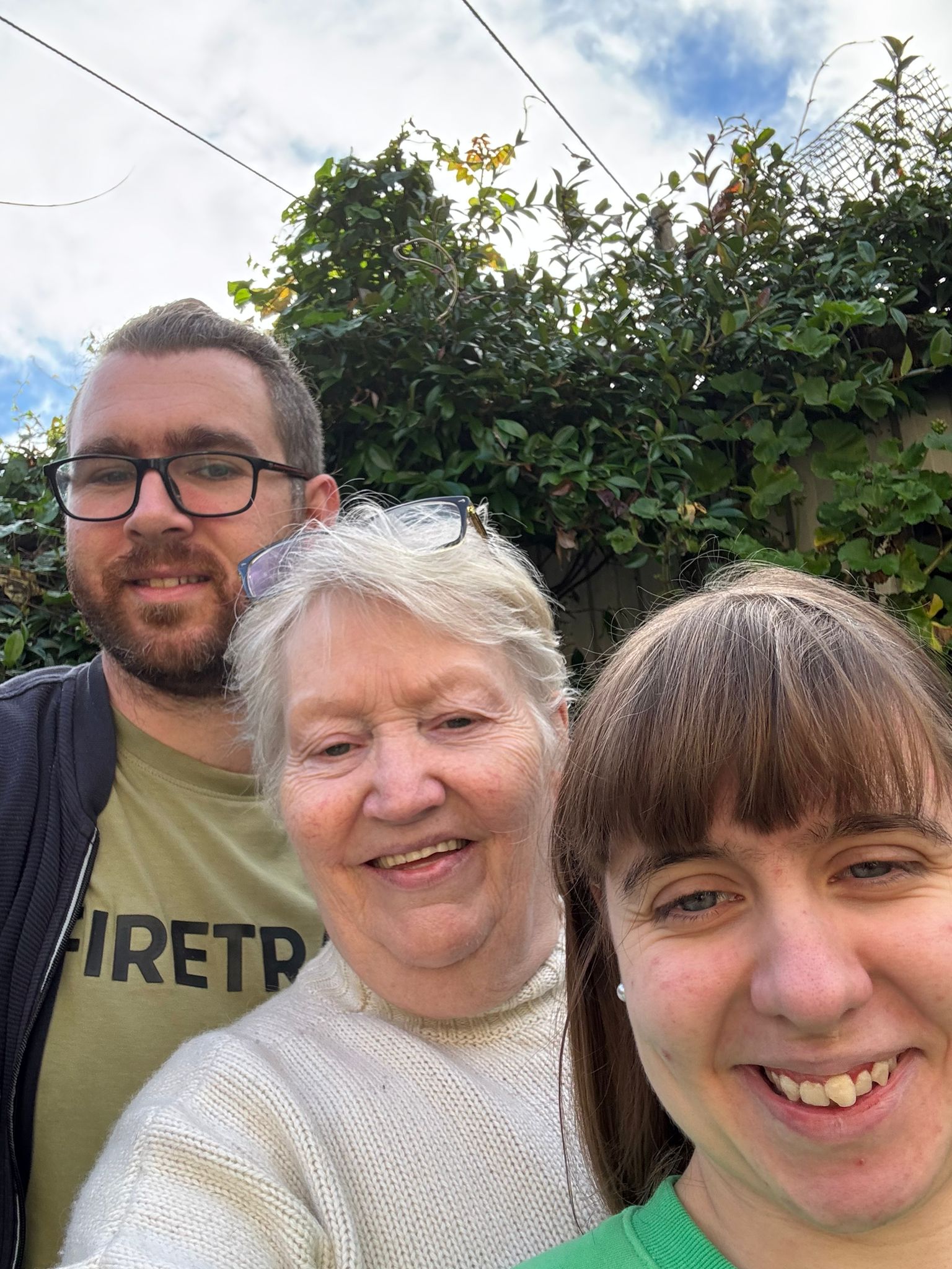 Shared Lives carer, Annie, stood smiling with the two young people she supports, Louise and Mikey. 