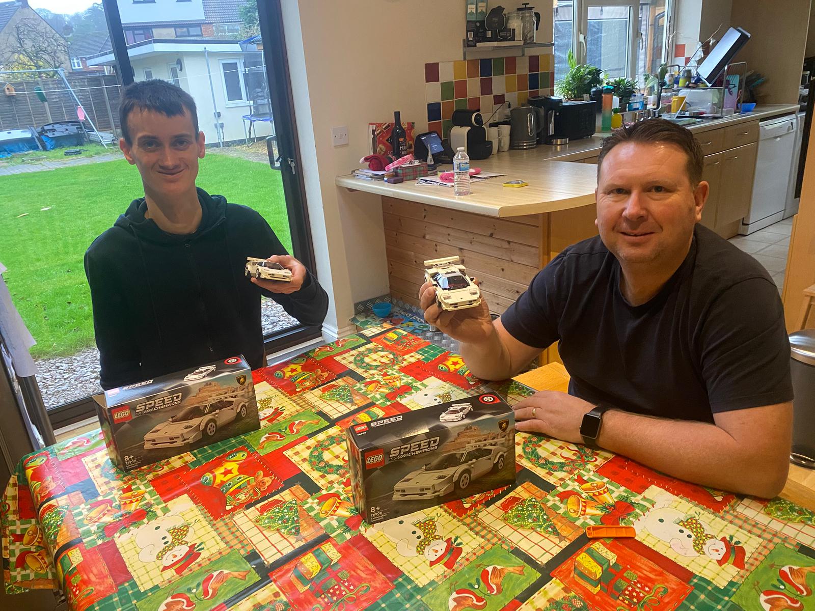 Shared Lives carer Neil and young Nathan holding up their cars from their lego set.