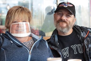 Trevor and his support worker Jayne smiling at the camera. Jayne is wearing a mask. 