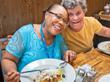 Two women eating lunch and smiling. 