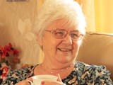 Grazelda, Shared Lives carer, drinking a cup of tea and smiling. 