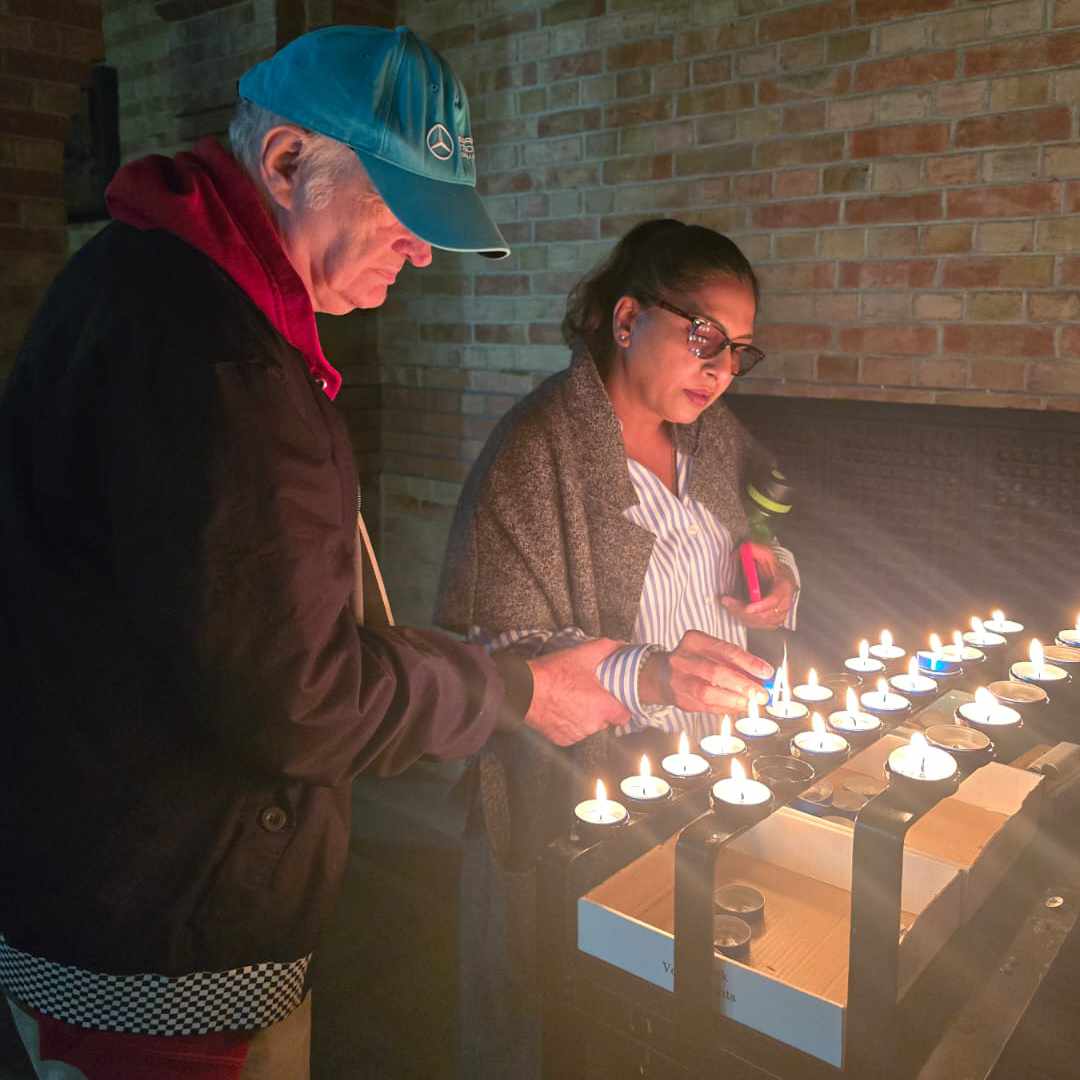 A picture of Alan lighting a candle in the church at Brading