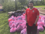 Danny stood in front of lots of full pink bink bags from litter picking. 
