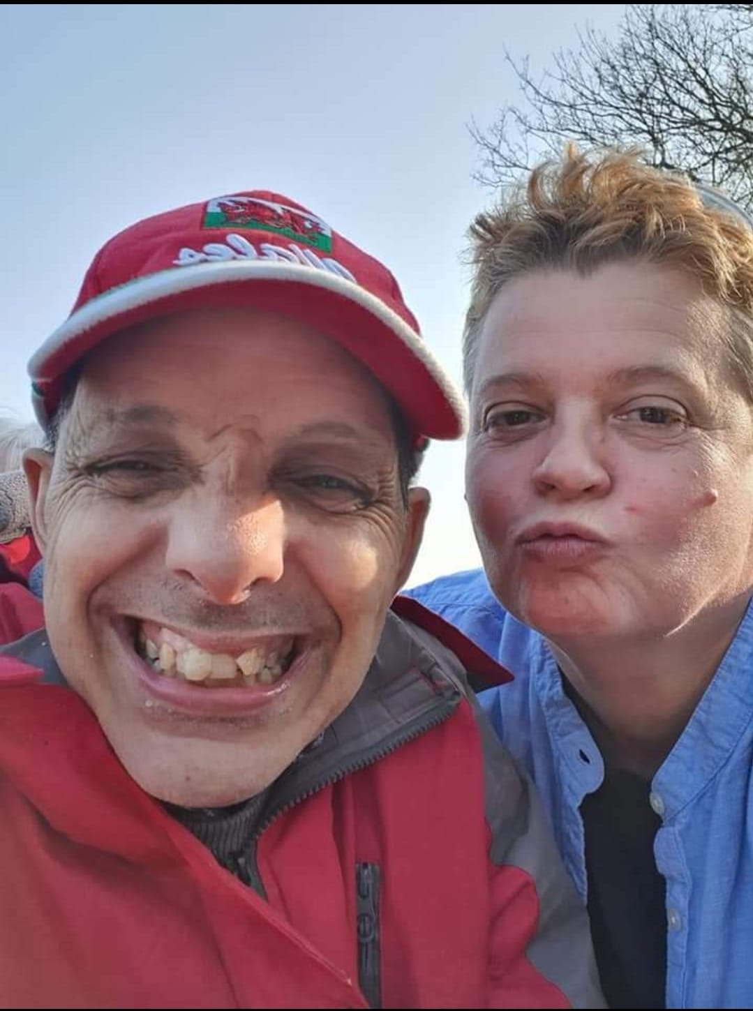 A man and a woman. the man is grinning at the camera and the woman is pouting a kiss. 