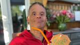 A man with downs syndrome sitting outside smiling with a fruity cocktail
